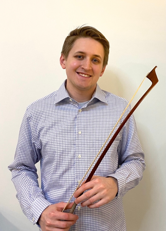 Man standing in front of a neutral wall holding a double bass bow