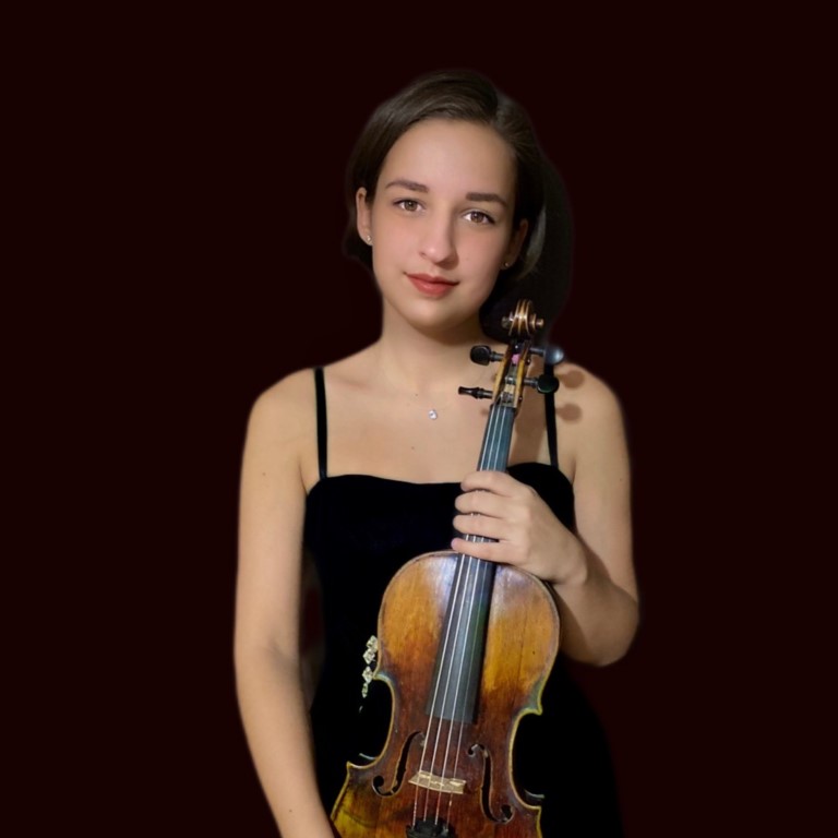 Woman wearing a black dress and necklace, smiling while holding a violin with both hands.