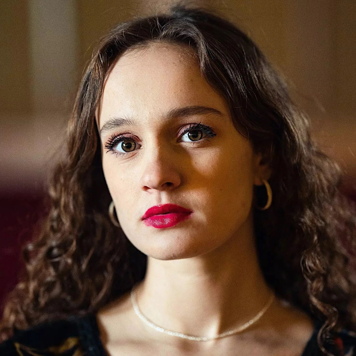 a person with long curly hair and red lipstick
